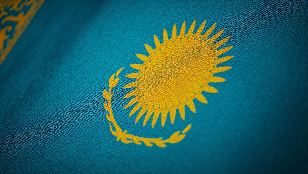 Kazakhstan Flag Close-Up Showing Golden Sun Emblem with Ornamental Stripe on Teal Fabric