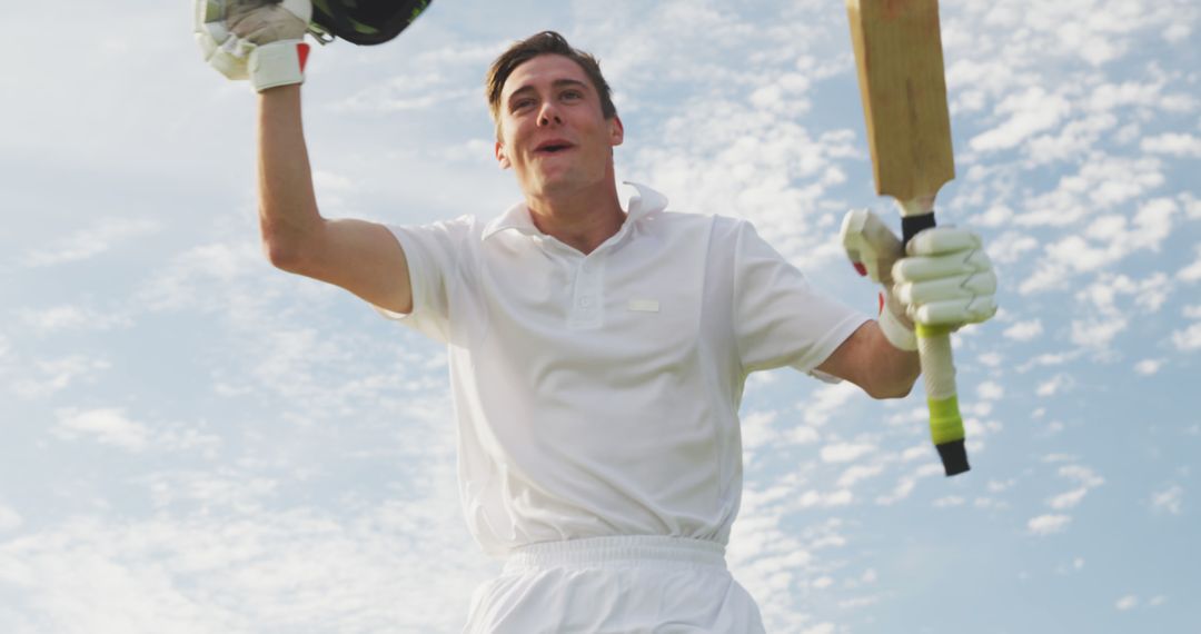 Cricketer Celebrating Victory with Raised Bat and Helmet - Free Images, Stock Photos and Pictures on Pikwizard.com