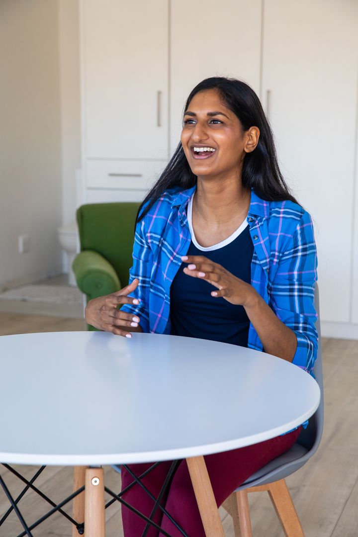 Smiling Woman Gesturing While Talking at Table in Modern Lounge