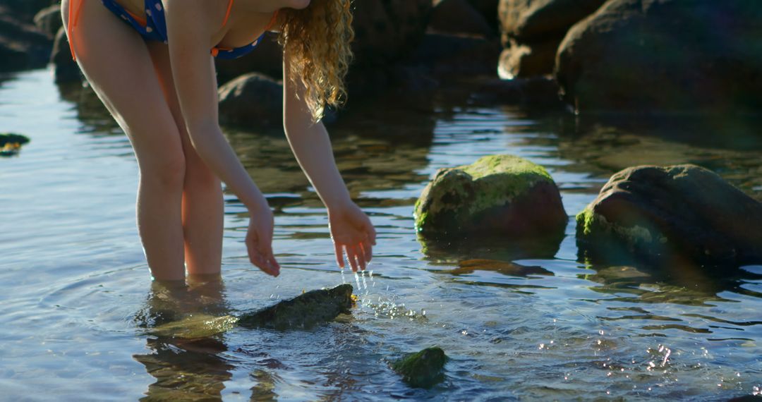 Woman exploring rocky shoreline with clear water - Free Images, Stock Photos and Pictures on Pikwizard.com