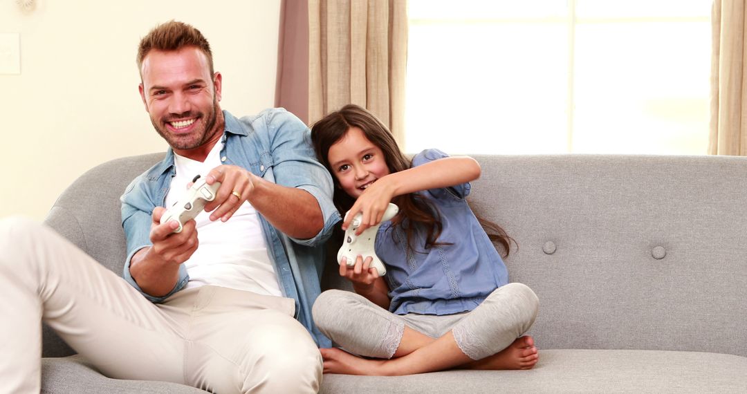 Father and Daughter Playing Video Games on Sofa Happily - Free Images, Stock Photos and Pictures on Pikwizard.com