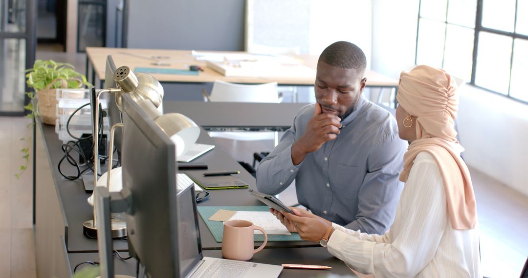 Colleagues Discussing Work in Modern Office with Tablet and Laptop