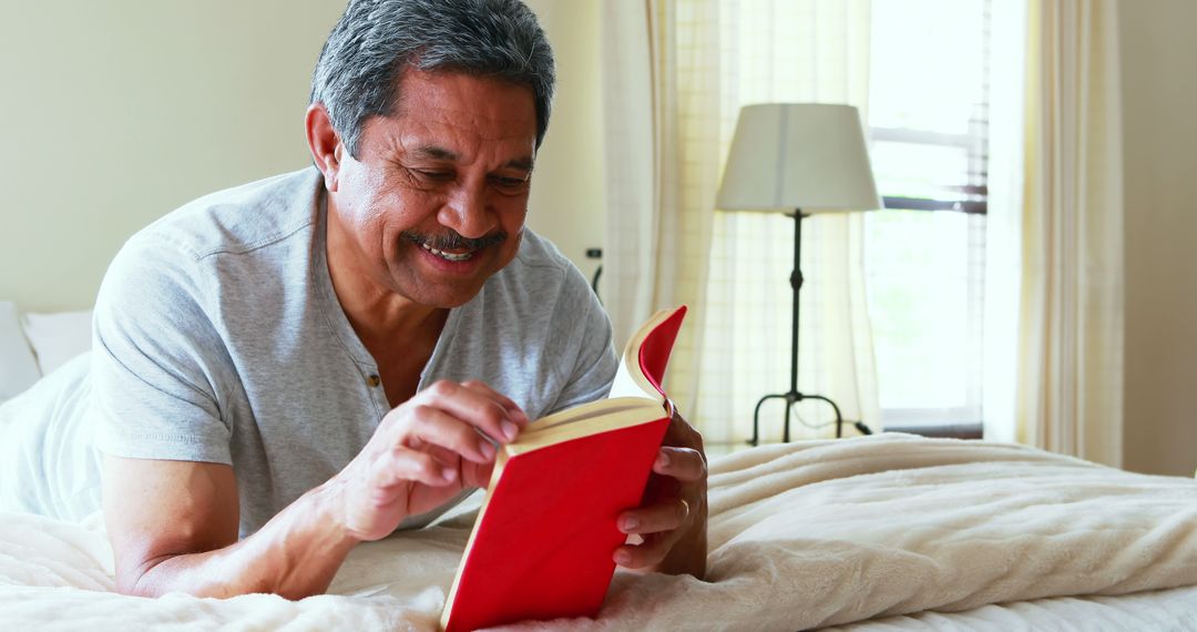 Older Man Reading a Book on Bed in Cozy Bedroom - Free Images, Stock Photos and Pictures on Pikwizard.com