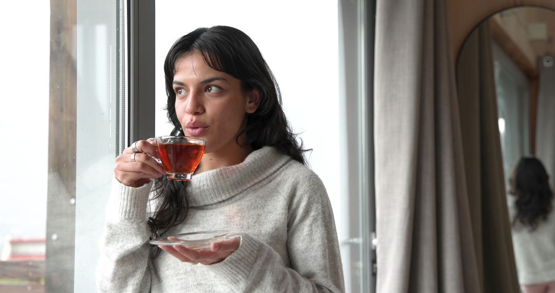 Woman Enjoying Tea by Window in Cozy Scandinavian Space