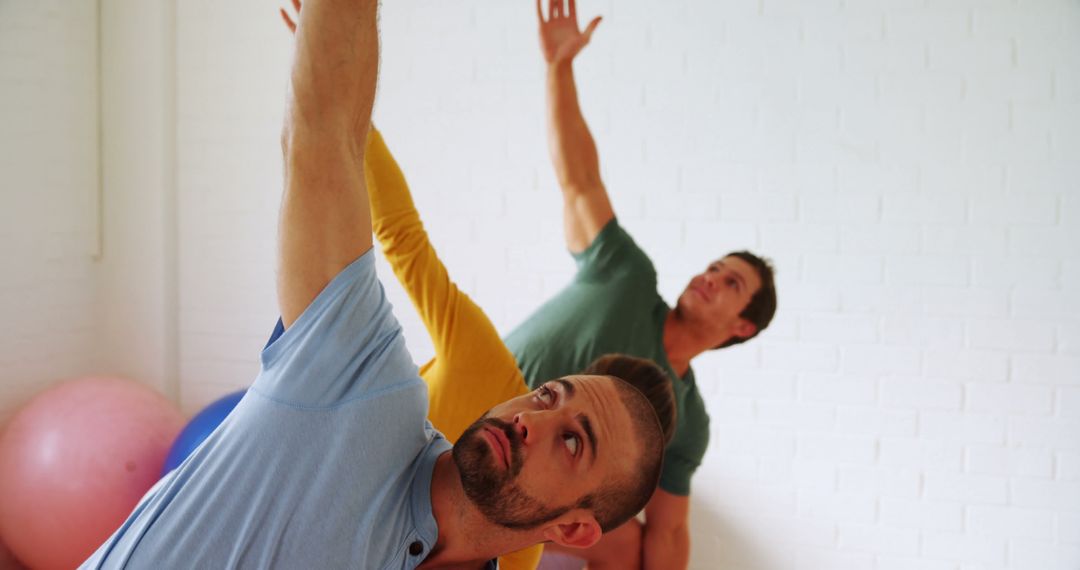 Two Men Practicing Yoga Together in Bright Studio - Free Images, Stock Photos and Pictures on Pikwizard.com