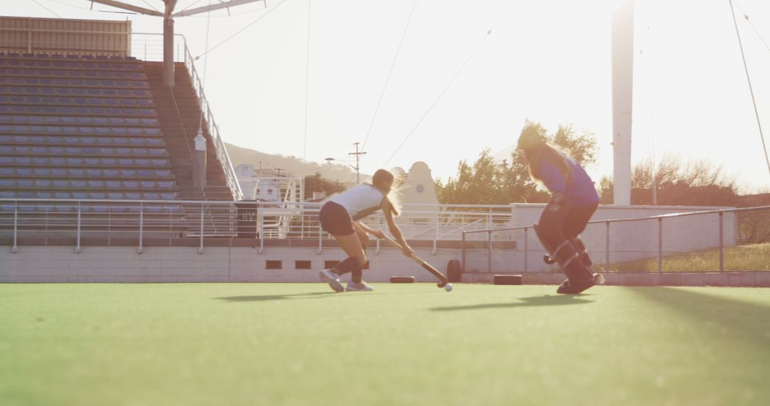 Two Women Playing Field Hockey at Outdoor Stadium During Sunset - Free Images, Stock Photos and Pictures on Pikwizard.com