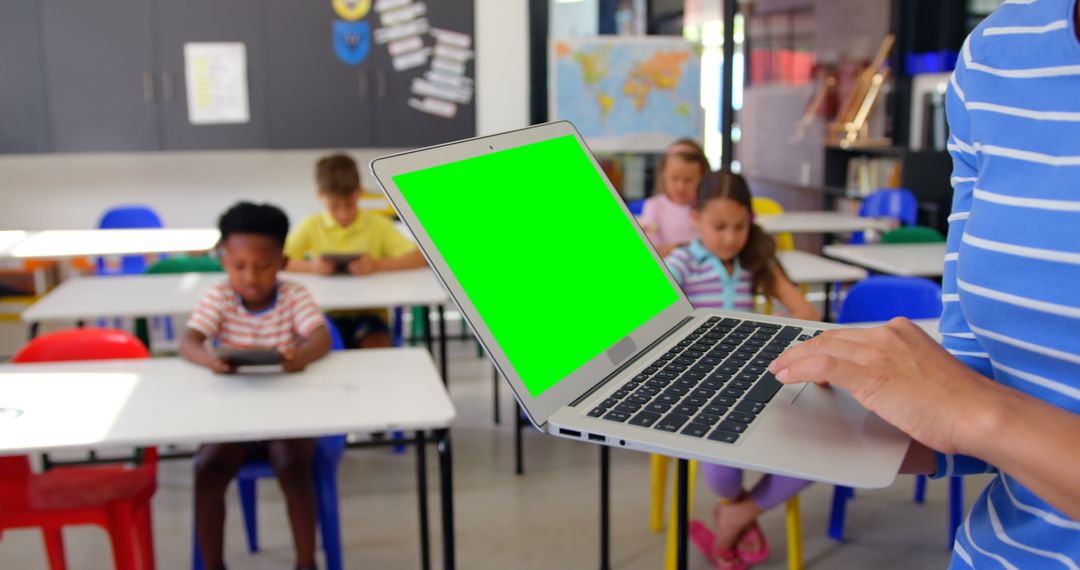Teacher Using Laptop with Children Studying in Classroom
