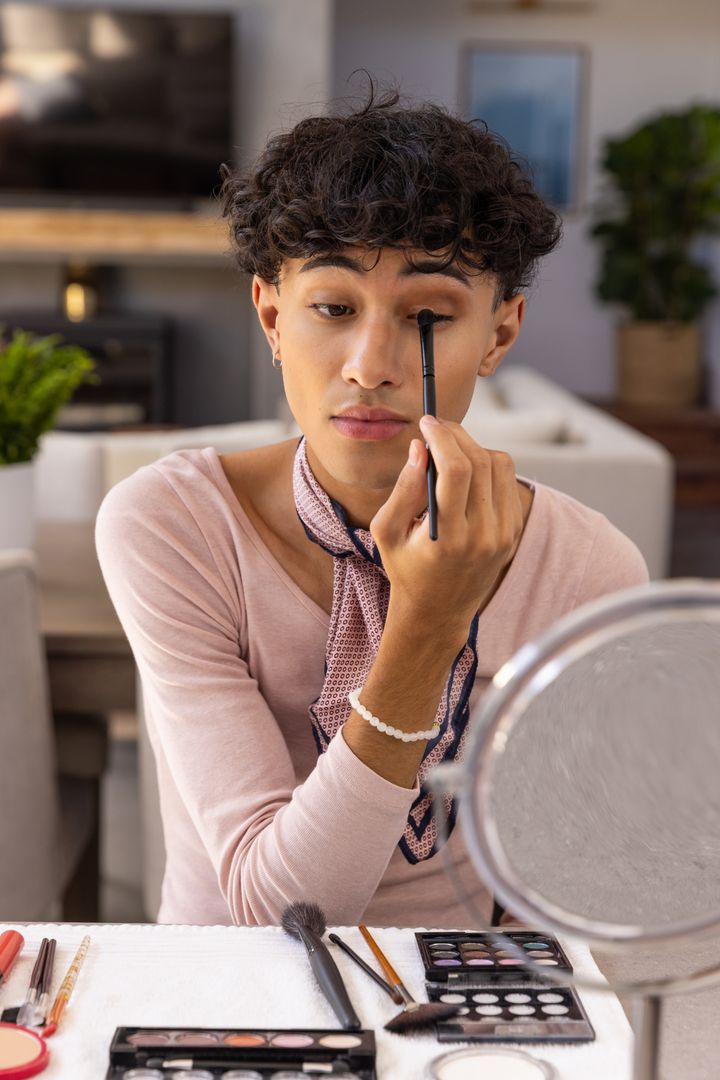 Young Male Applying Eyeshadow Using Mirror in Living Room