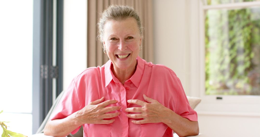 Happy Senior Woman in Pink Shirt Enjoying Moment Indoors