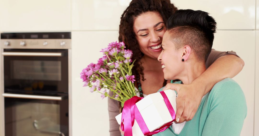 Joyful Couple Celebrating with Flowers and Gift in Kitchen - Free Images, Stock Photos and Pictures on Pikwizard.com