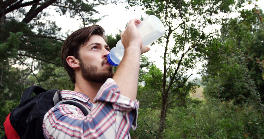 Young Man Hydrating While Hiking in Forest - Free Images, Stock Photos and Pictures on Pikwizard.com