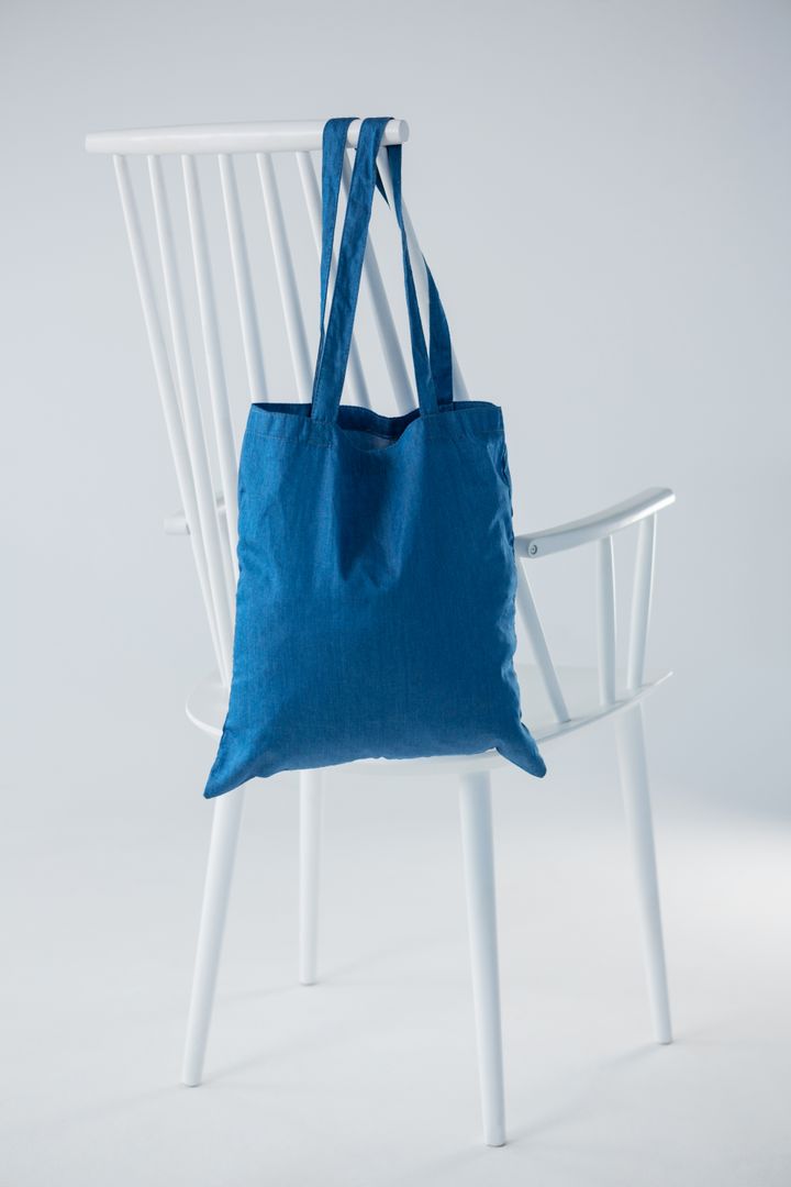 Blue bag hanging on a white chair - Free Images, Stock Photos and Pictures on Pikwizard.com