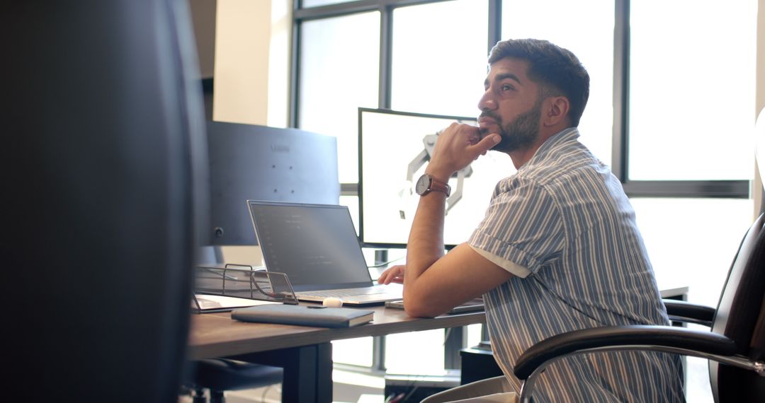 Man Contemplating in Modern Office with Laptop and Robotic Arm