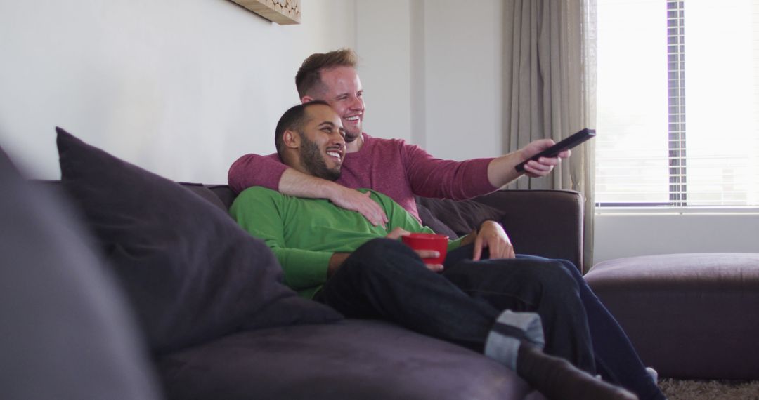 Smiling Multi-Ethnic Gay Couple Watching TV at Home