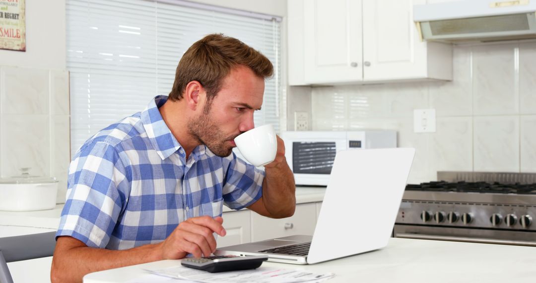 Man working on laptop while drinking coffee in modern kitchen - Free Images, Stock Photos and Pictures on Pikwizard.com