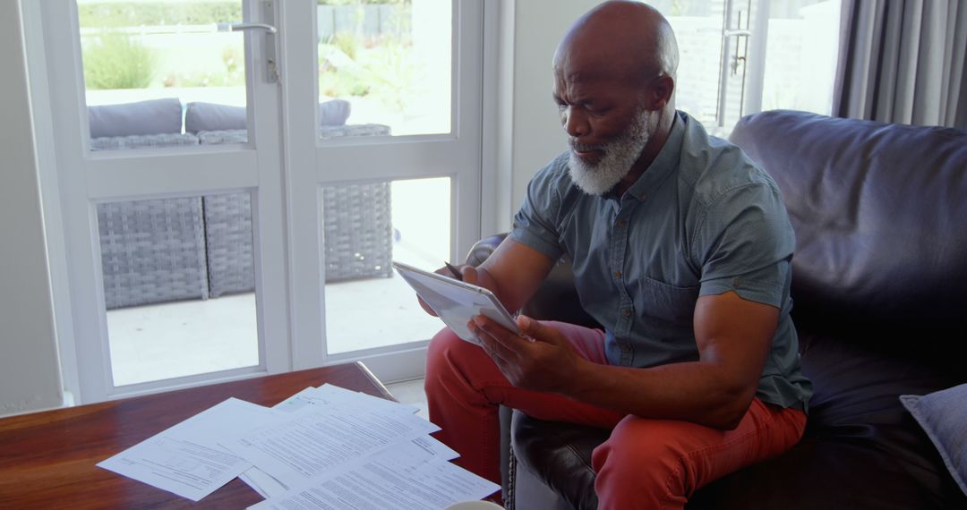 Senior man reviewing financial documents at home on a tablet - Free Images, Stock Photos and Pictures on Pikwizard.com