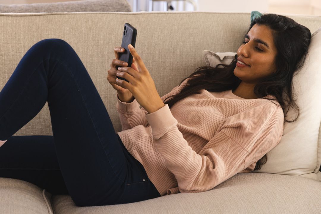 Woman Relaxing on Sofa with Smartphone in Cozy Home Environment