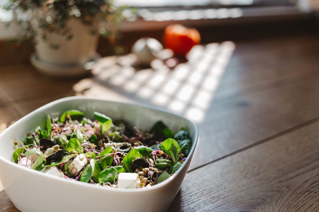 Serving fresh microgreen salad with feta, sprouts and seeds on sunlit wooden table