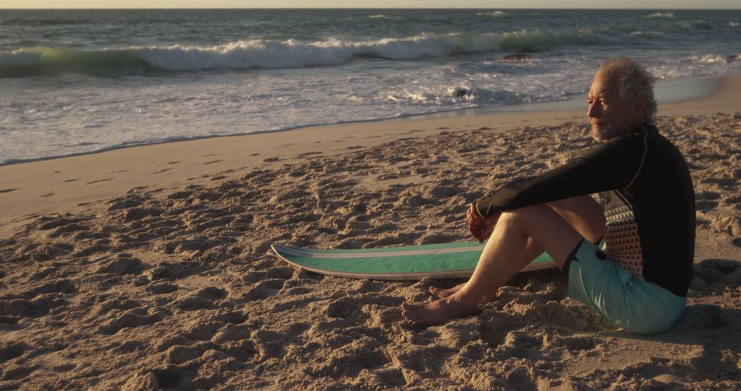 Senior A Surfer Relaxing on Beach with Surfboard at Sunset - Free Images, Stock Photos and Pictures on Pikwizard.com