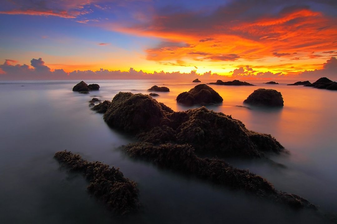 Mesmerizing Sunset Over Rocky Seashore with Silky Water - Free Images, Stock Photos and Pictures on Pikwizard.com