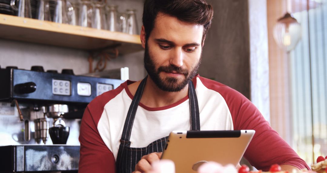 Young Male Barista Using Digital Tablet in Coffee Shop - Free Images, Stock Photos and Pictures on Pikwizard.com