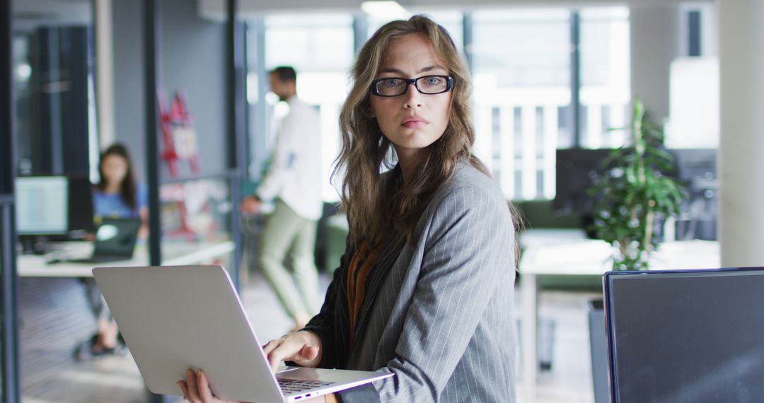 Focused Businesswoman Holding Laptop in Modern Office - Free Images, Stock Photos and Pictures on Pikwizard.com