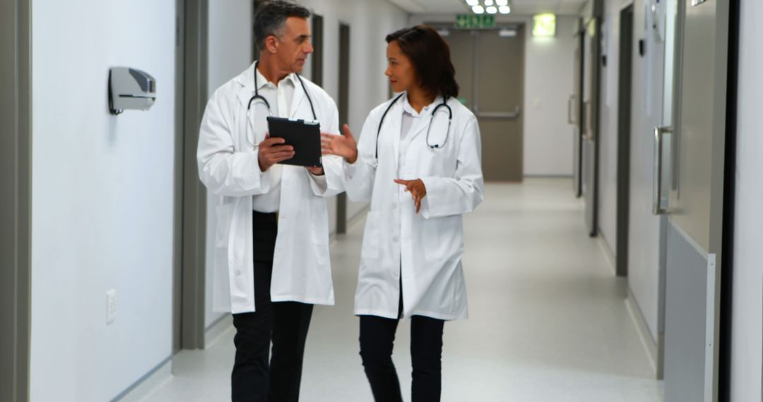 Two Doctors Discussing Patient Records in Hospital Corridor - Free Images, Stock Photos and Pictures on Pikwizard.com