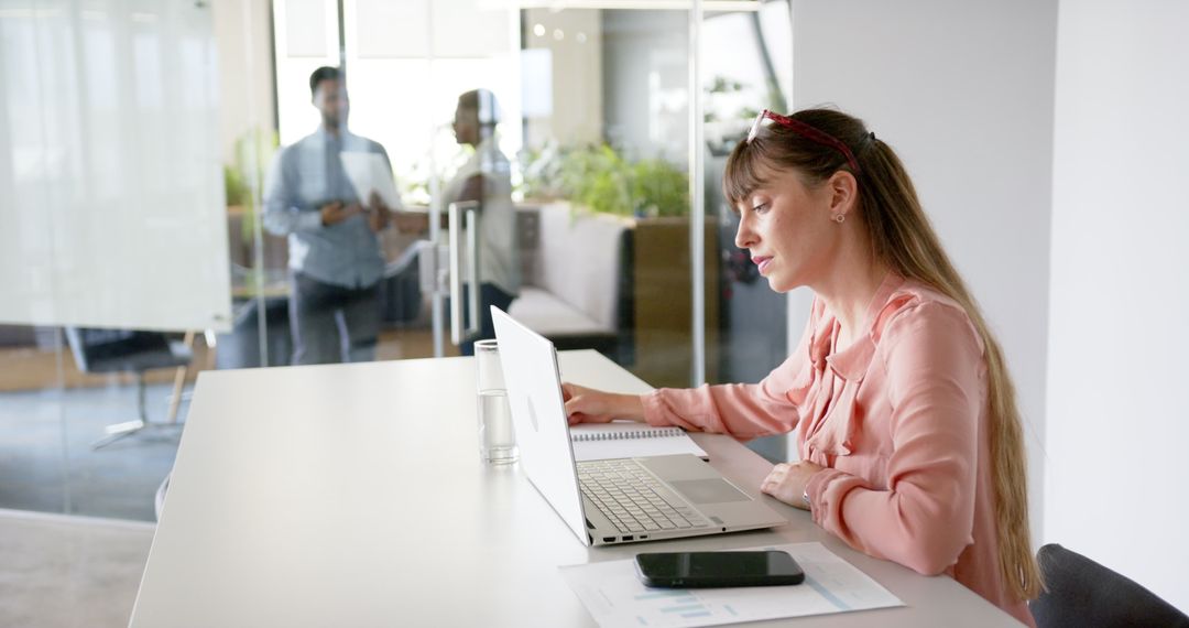 Businesswoman Working on Laptop and Taking Notes in Office