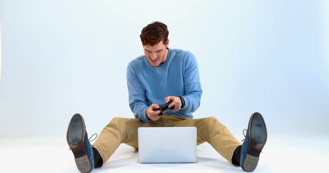 Young Man Smiling While Gaming with Laptop and Controller - Free Images, Stock Photos and Pictures on Pikwizard.com