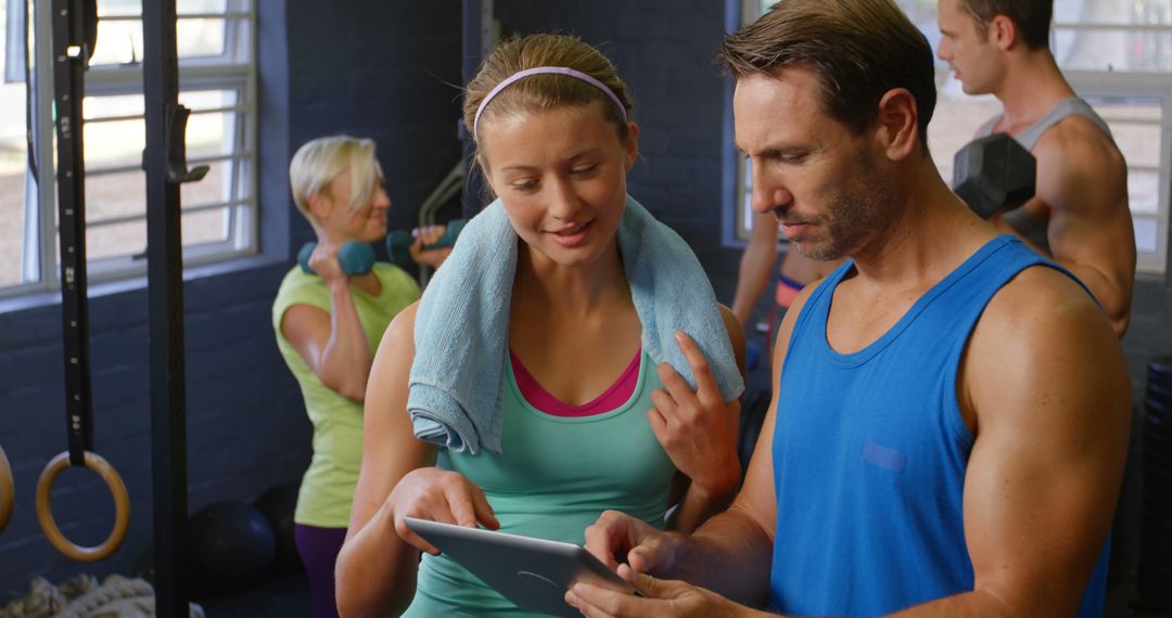 Personal Trainer Guiding Female Client on Tablet - Free Images, Stock Photos and Pictures on Pikwizard.com