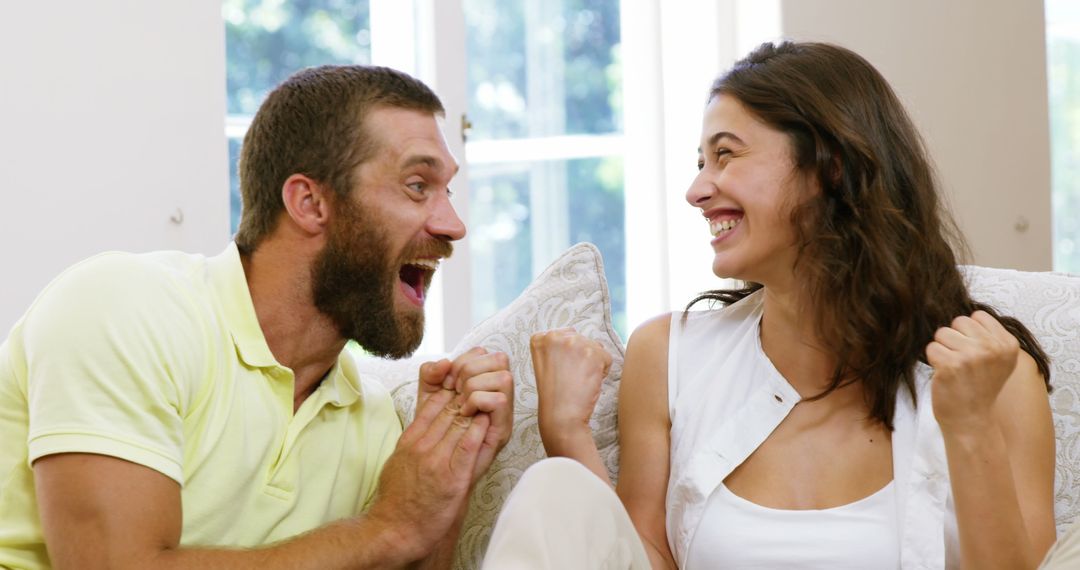 Excited Couple Sharing a Joyful Moment on Sofa - Free Images, Stock Photos and Pictures on Pikwizard.com