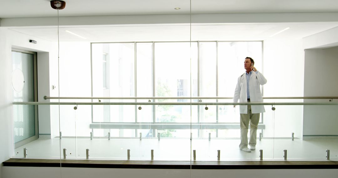 Doctor Standing in Modern Hospital Hallway Using Mobile Phone - Free Images, Stock Photos and Pictures on Pikwizard.com