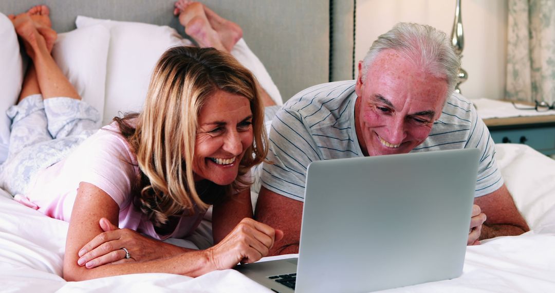 Happy Senior Couple Using Laptop Together On Bed - Free Images, Stock Photos and Pictures on Pikwizard.com