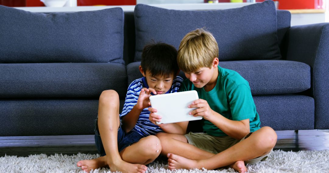 Two Young Boys Using Tablet While Sitting on Carpet - Free Images, Stock Photos and Pictures on Pikwizard.com