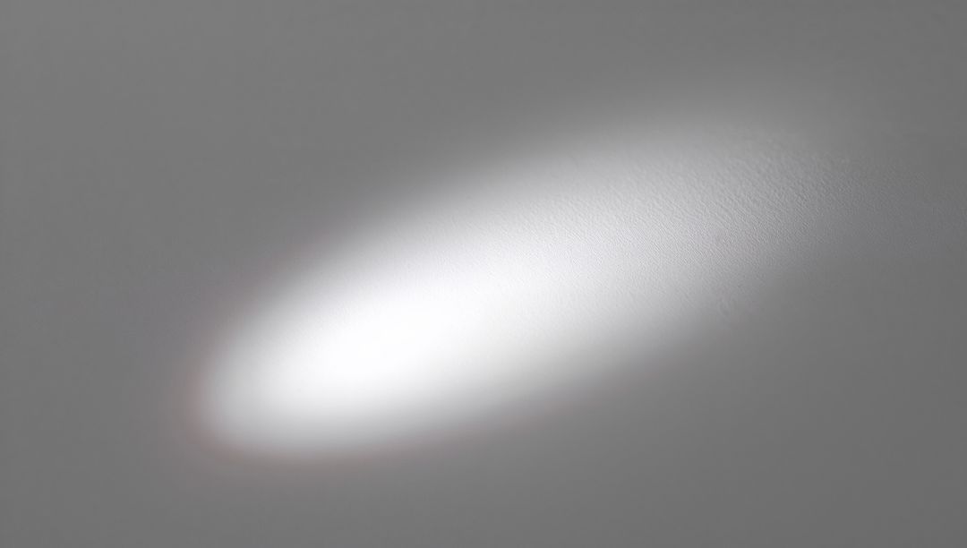 Soft Oval Spotlight Casting on Light Gray Plaster Wall with Subtle Texture