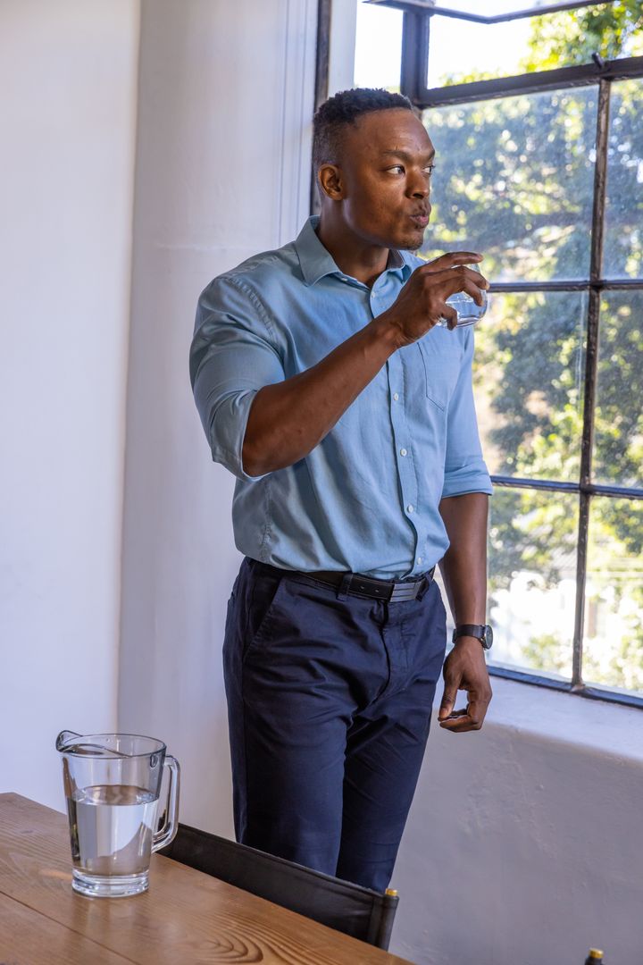 Professional Man Hydrating in Sunlit Office Setting
