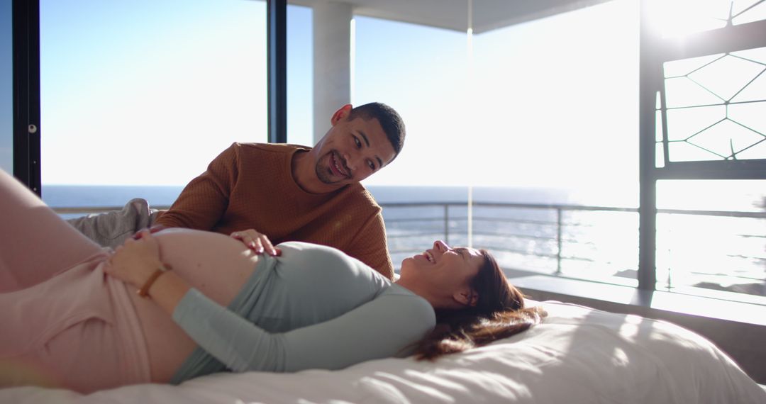Expectant Couple Relaxing and Enjoying Ocean View in Bedroom