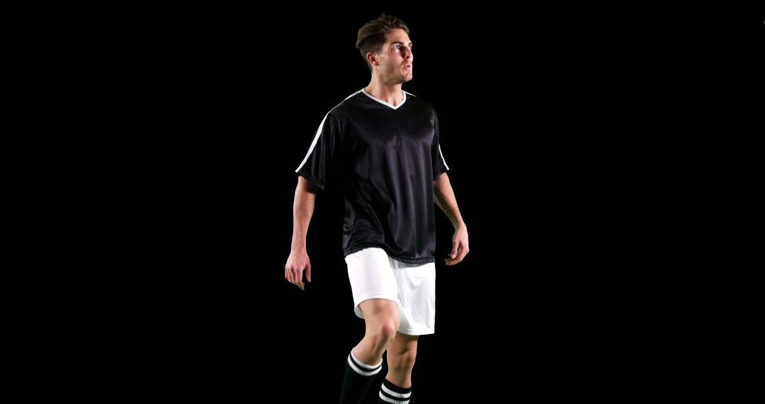 Confident Soccer Player Walking in Black and White Uniform on Black Background - Free Images, Stock Photos and Pictures on Pikwizard.com