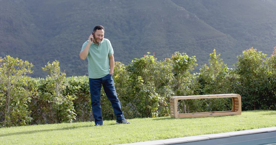Man Talking on Smartphone Outdoors by Poolside with Mountain Scenic