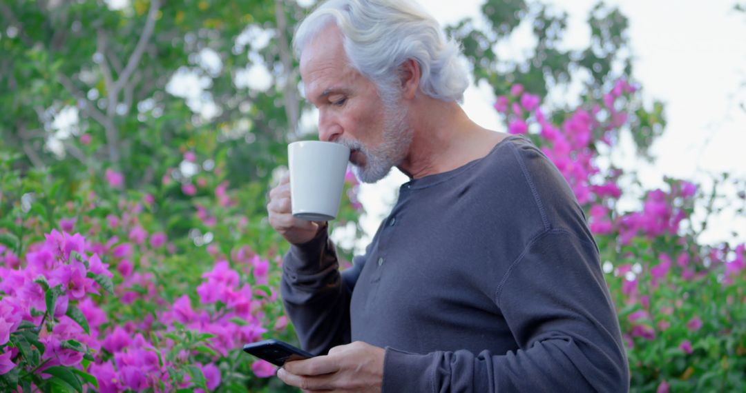 Elderly Man Enjoying Morning Coffee While Using Smartphone in Garden - Free Images, Stock Photos and Pictures on Pikwizard.com