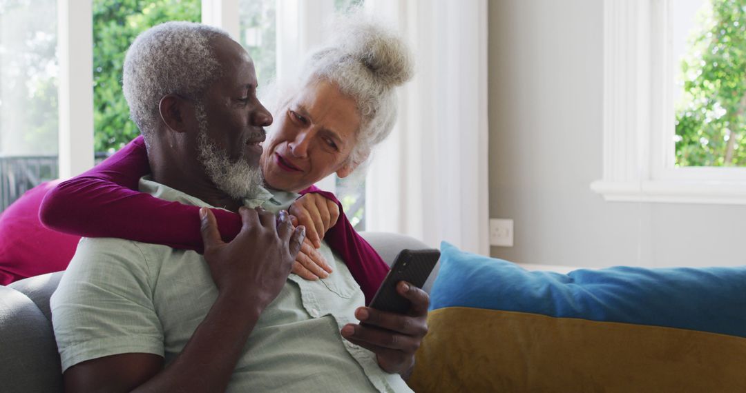 Loving Senior Couple Sharing Moment Sitting on Sofa with Smartphone - Free Images, Stock Photos and Pictures on Pikwizard.com