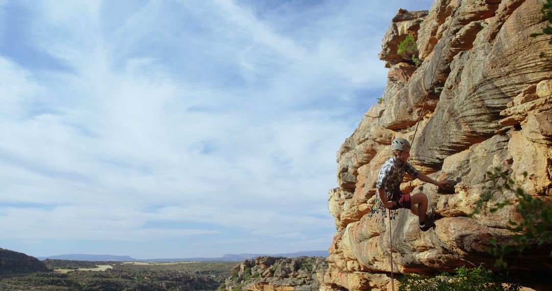 Adventurer Climbing Rocky Cliff in Scenic Desert Landscape - Free Images, Stock Photos and Pictures on Pikwizard.com