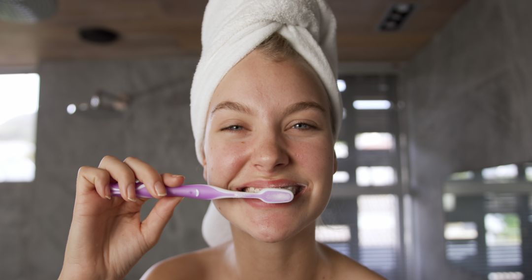 Young Woman Brushing Teeth in Bathroom with Towel Wrapped on Head - Free Images, Stock Photos and Pictures on Pikwizard.com