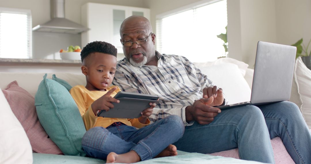 Grandfather and Grandson Using Tablet and Laptop in Living Room - Free Images, Stock Photos and Pictures on Pikwizard.com