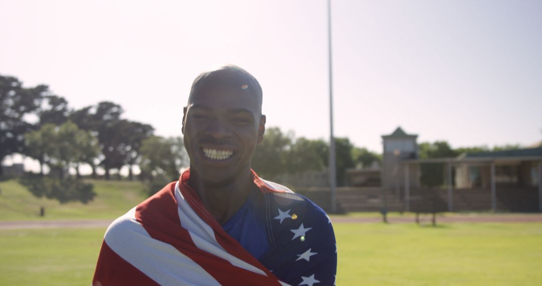 Smiling Athlete Draped in American Flag on Outdoor Track Field - Free Images, Stock Photos and Pictures on Pikwizard.com