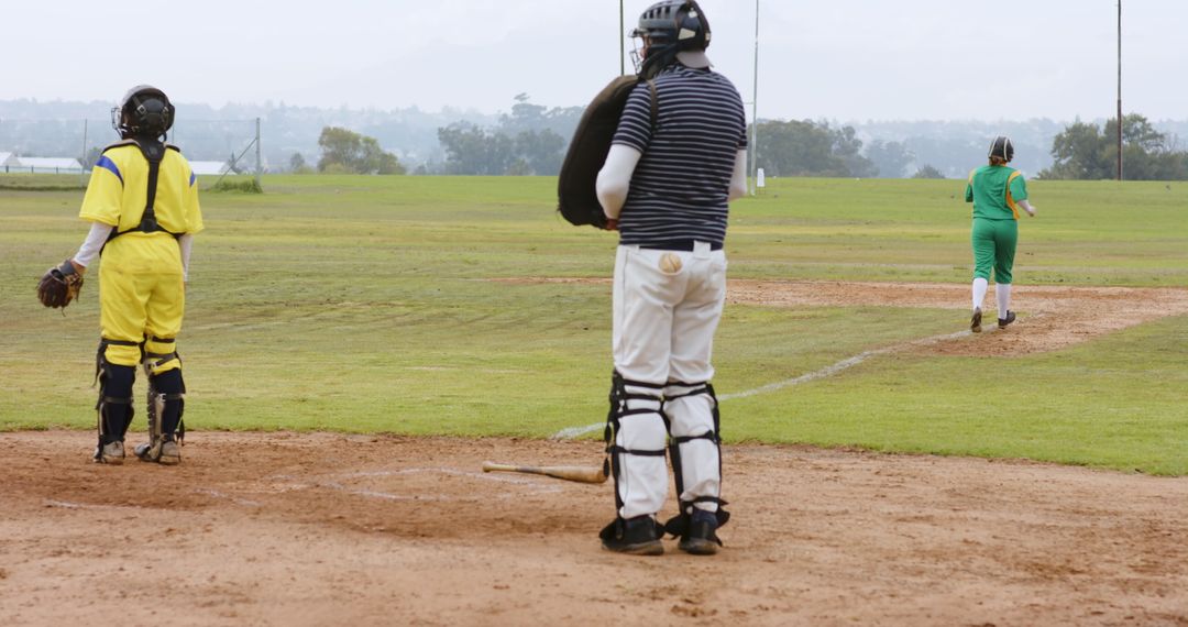 Youth Softball Game with Players in Catcher Gear in the Infield