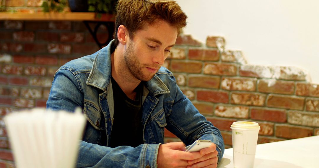 Young Man Using Smartphone in Cafe - Free Images, Stock Photos and Pictures on Pikwizard.com