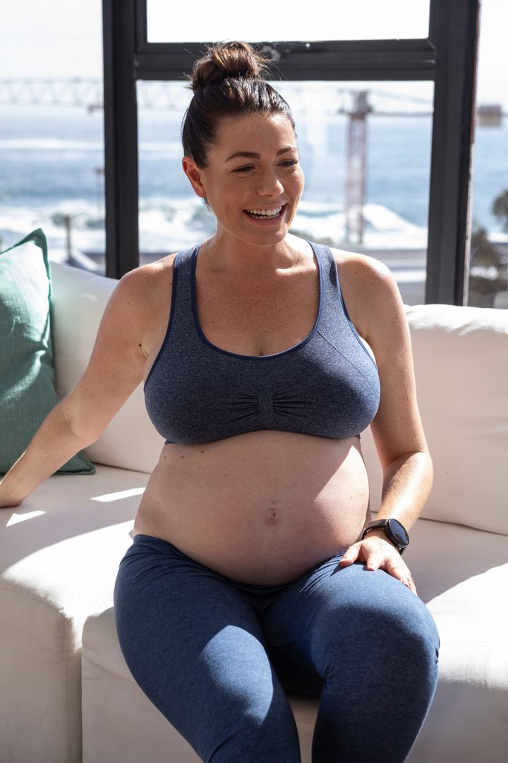 Pregnant Woman Relaxing by Ocean View Window in Comfortable Activewear