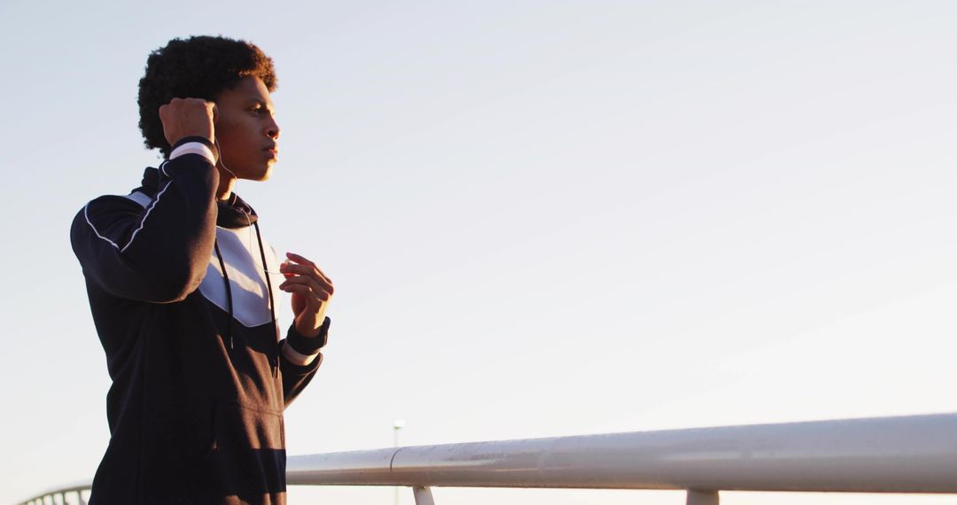 Athletic Runner Preparing with Earbuds on Pedestrian Bridge at Dawn
