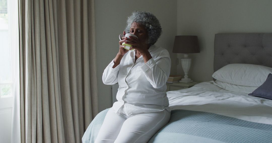 Senior Woman Drinking Coffee and Relaxing on Bed in Morning Light - Free Images, Stock Photos and Pictures on Pikwizard.com